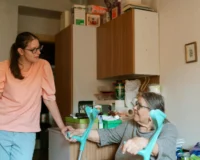 elderly woman sitting with crunches talking to a nurse in a home