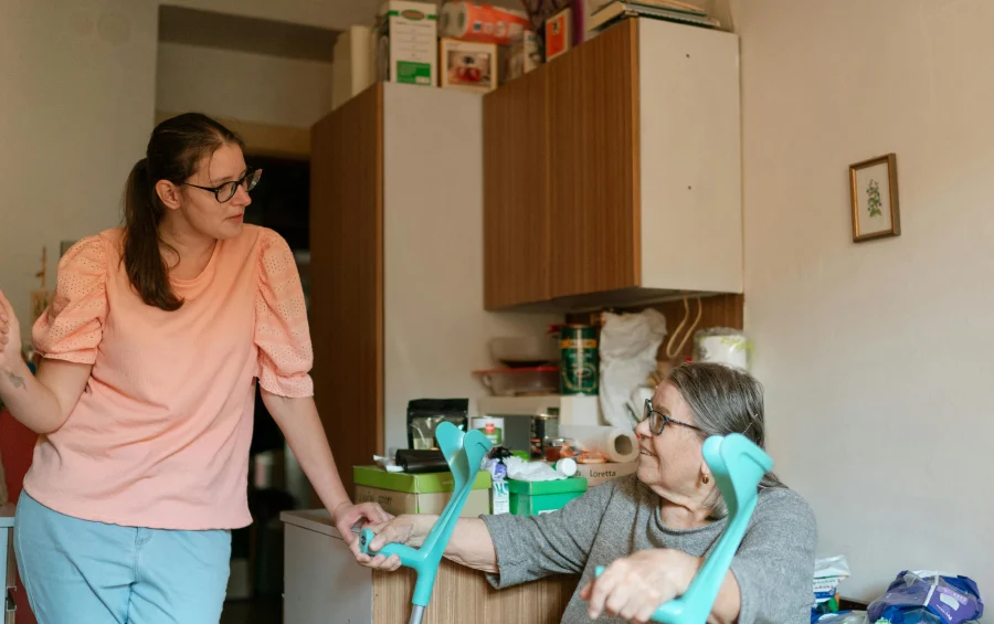 elderly woman sitting with crunches talking to a nurse in a home