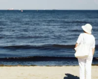 elderly woman standing at the beach and admiring the sea