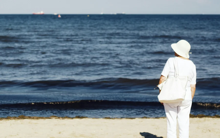 elderly woman standing at the beach and admiring the sea